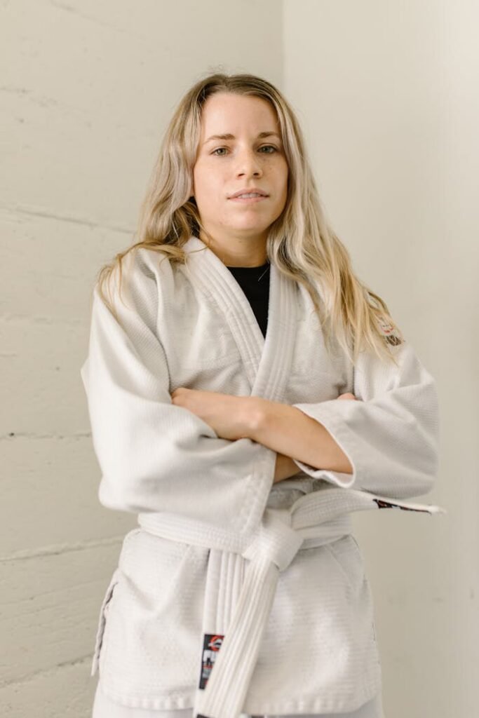 Portrait of a confident woman in a martial arts uniform with a white belt.