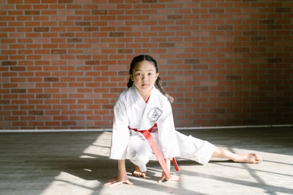 A young girl practicing martial arts indoors, showcasing concentration in her gi.